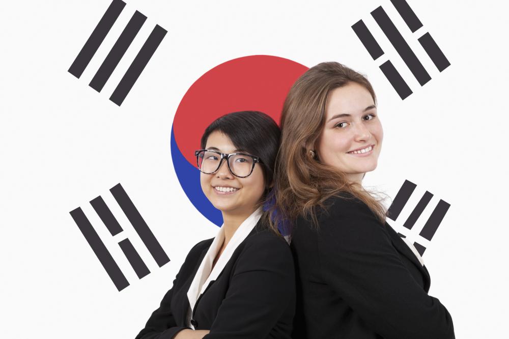 Two businesswomen standing back to back over a South Korean flag, indicating international business expansion and PEO services